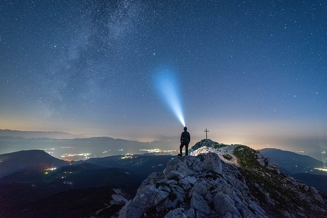 Man at mountain summit, light projecting into the sky, 5 ps of success