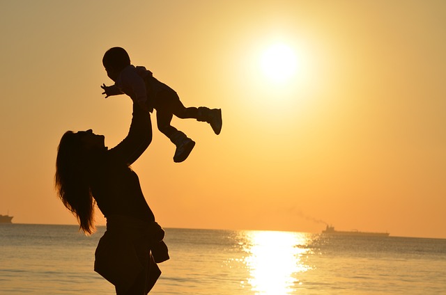 Woman holding baby up in the air on the beach, how to be happy, how to be happier, happiness