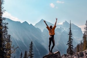 Woman on mountain summit with her arms up in the air, how to habit stack