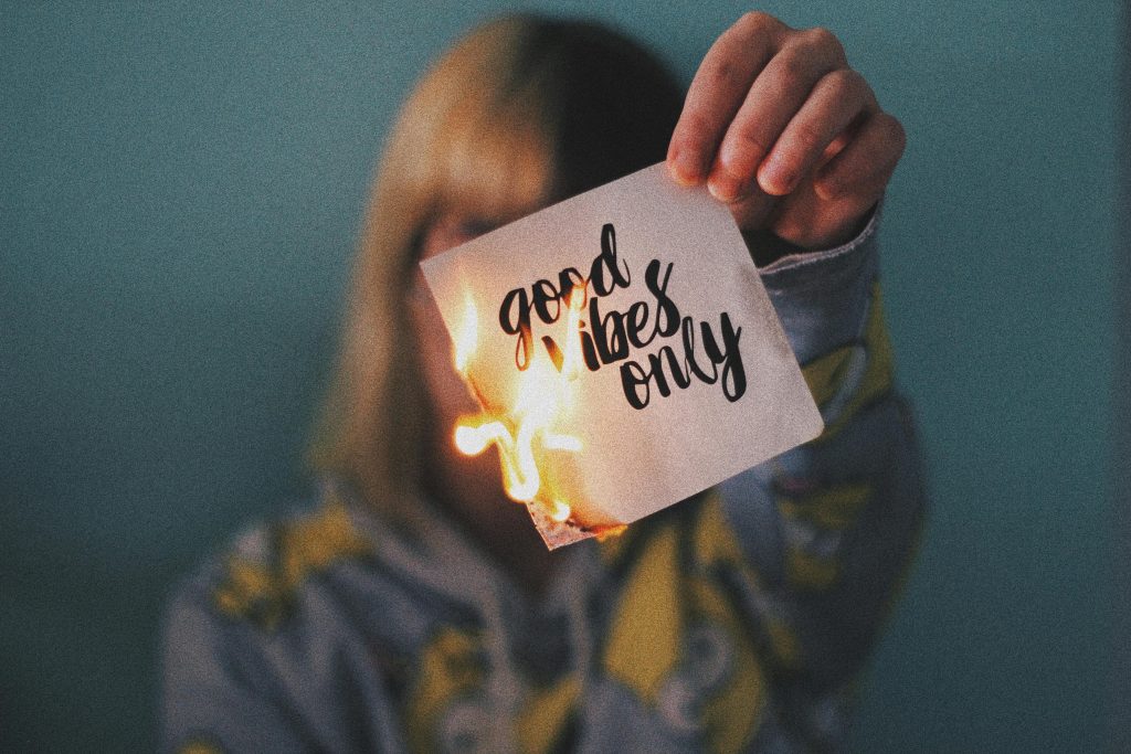 Woman burning a piece of paper that reads "good vibes only," decorative, how to recover from burnout, burnout recovery, burnout