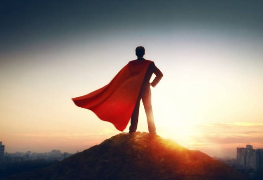 Man with cape superman standing on mountain summit, decorative